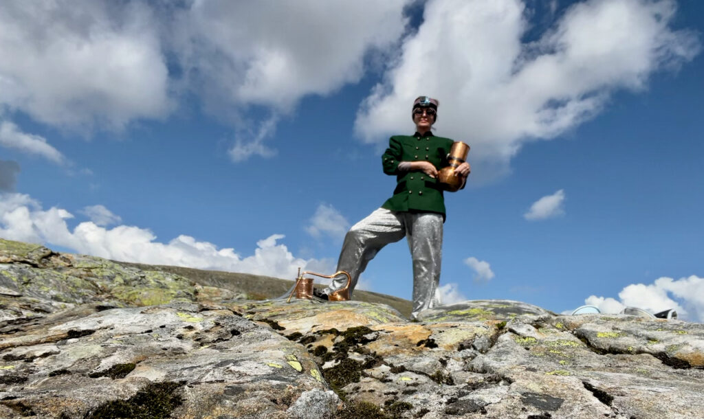 The performer standing on a rock holding a still.